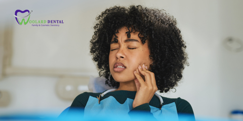 woman holding her mouth tooth in pain at the dentist